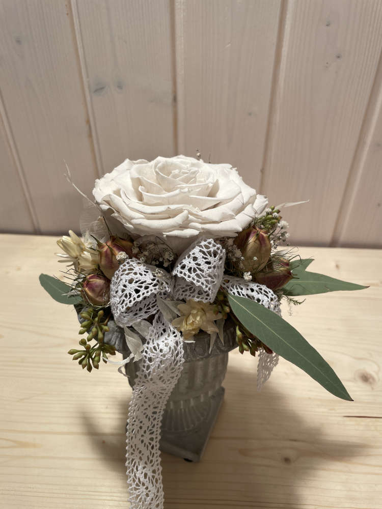 Eine weisse getrocknete Rose auf einer kleine Säule