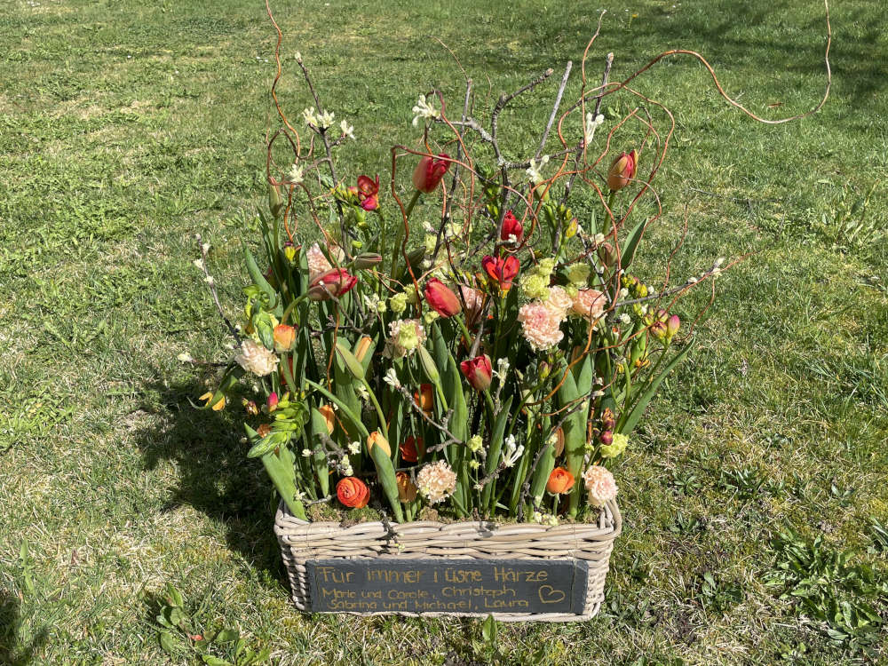 Ein Abschiedsdekoration im Korb mit einer beschriebene Schieferplatte.