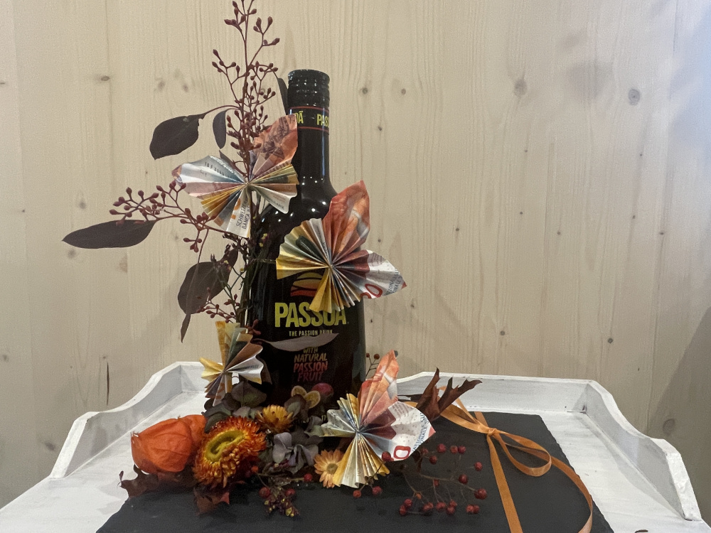 Eine Flasche die mit Blumen ausgarngiert ist zu schenken.