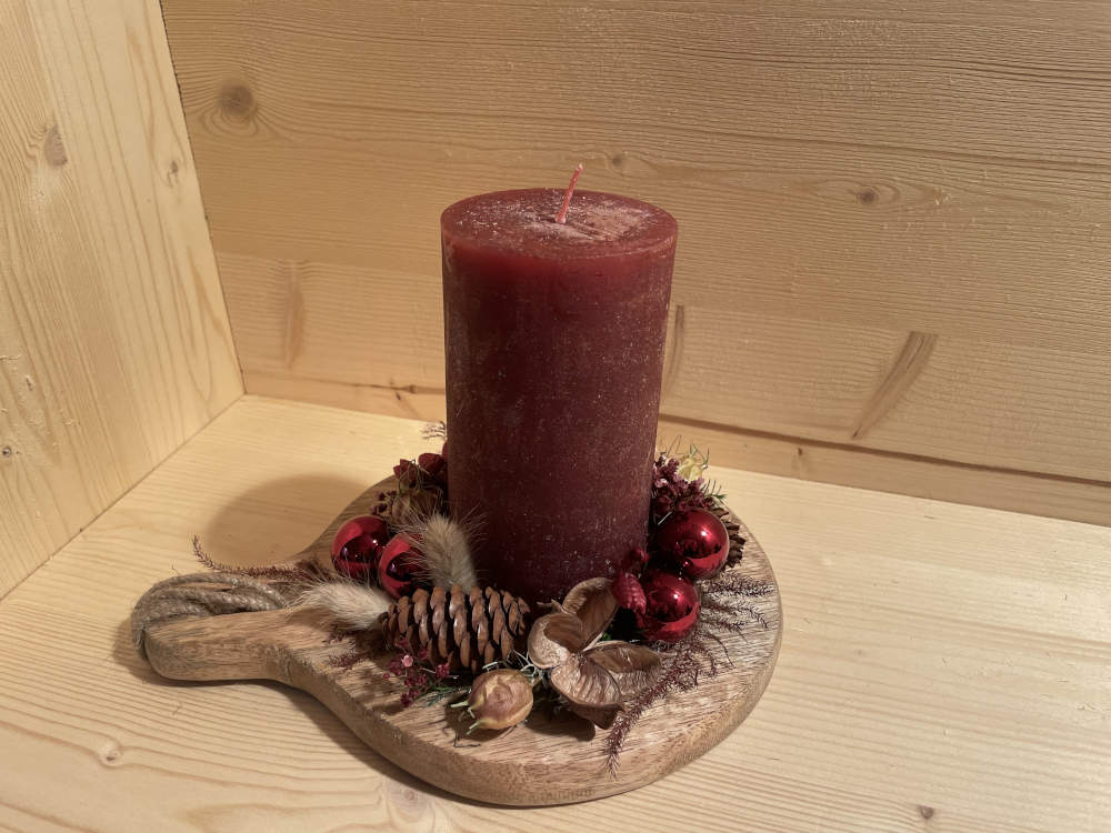 Rote Kerze aus einem Brett weihnahtlich ausgarniert