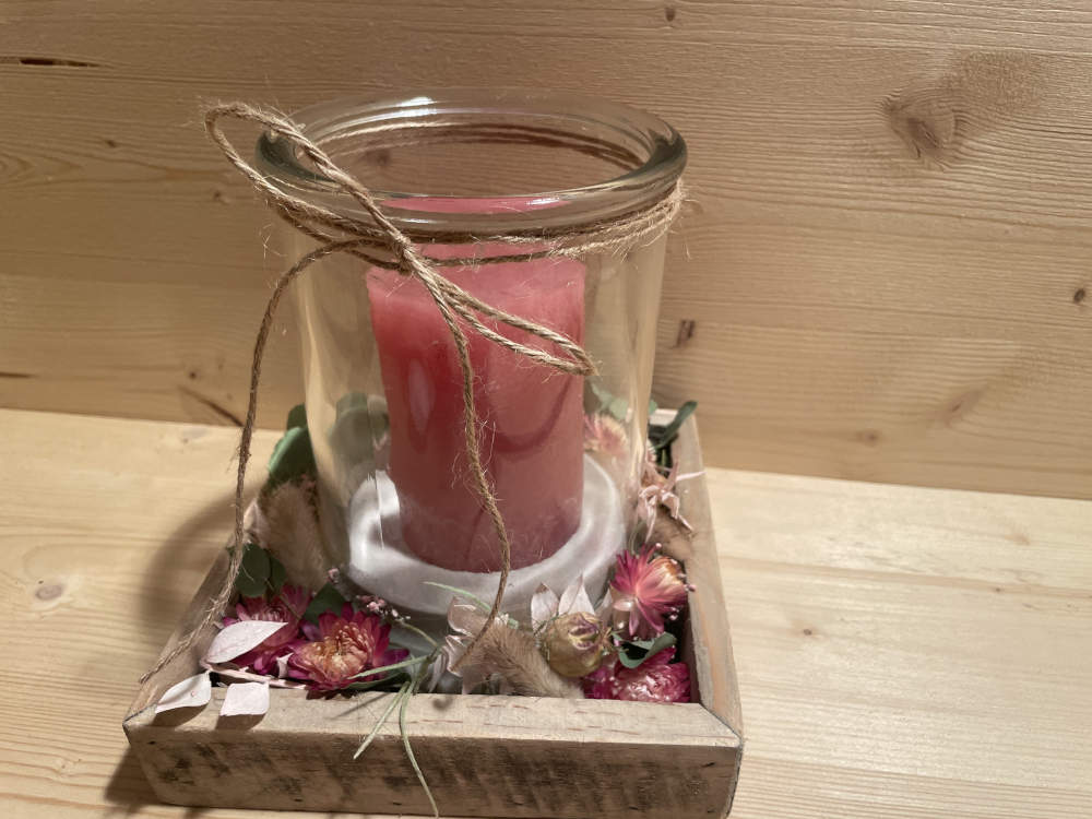 Glas auf einem Hozltablett schöne ausdekoriert. mit einer Kerze im Glas