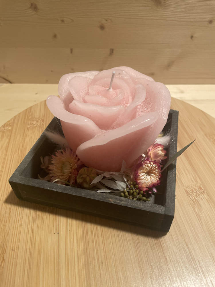 Rosenkerze in rosa auf einem Holztabeltt ausgarniert