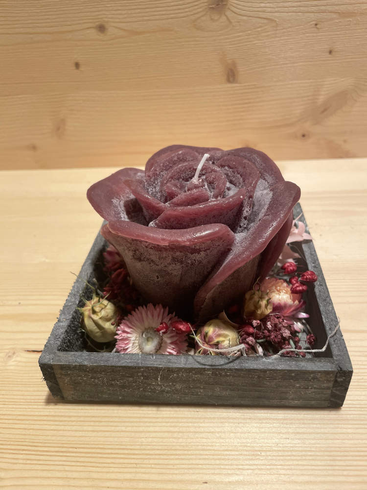 asugarnierte Rosenkerze in dunkelrot, ausgarniert auf einem Holztablett