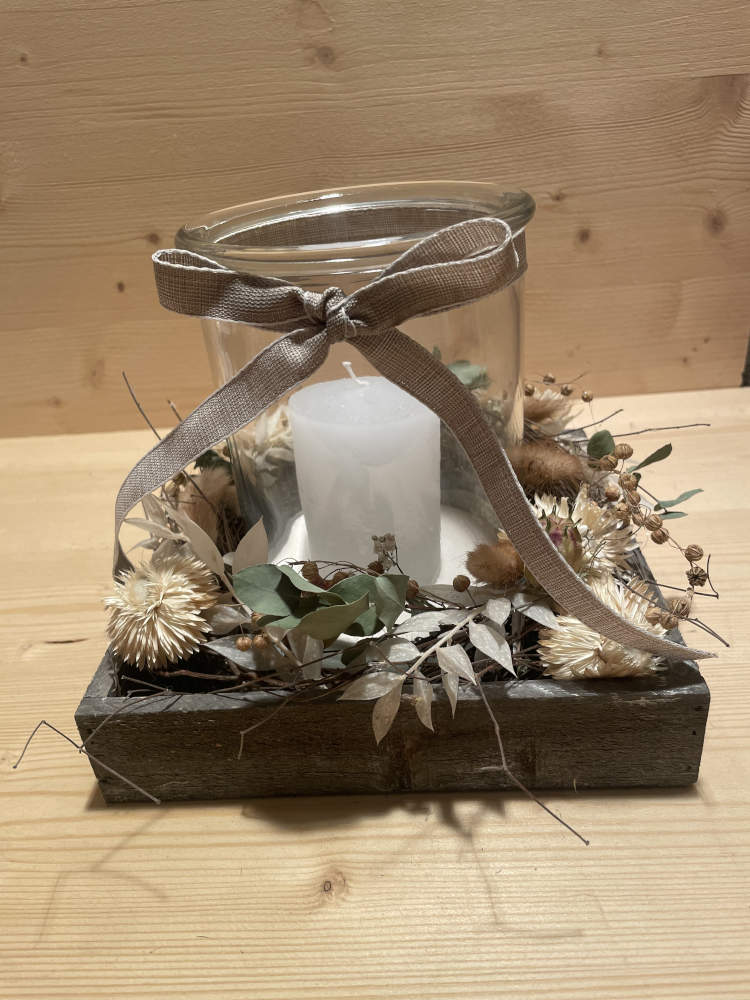 Kerze im Glas auf einem Holzbrett ausgarniert