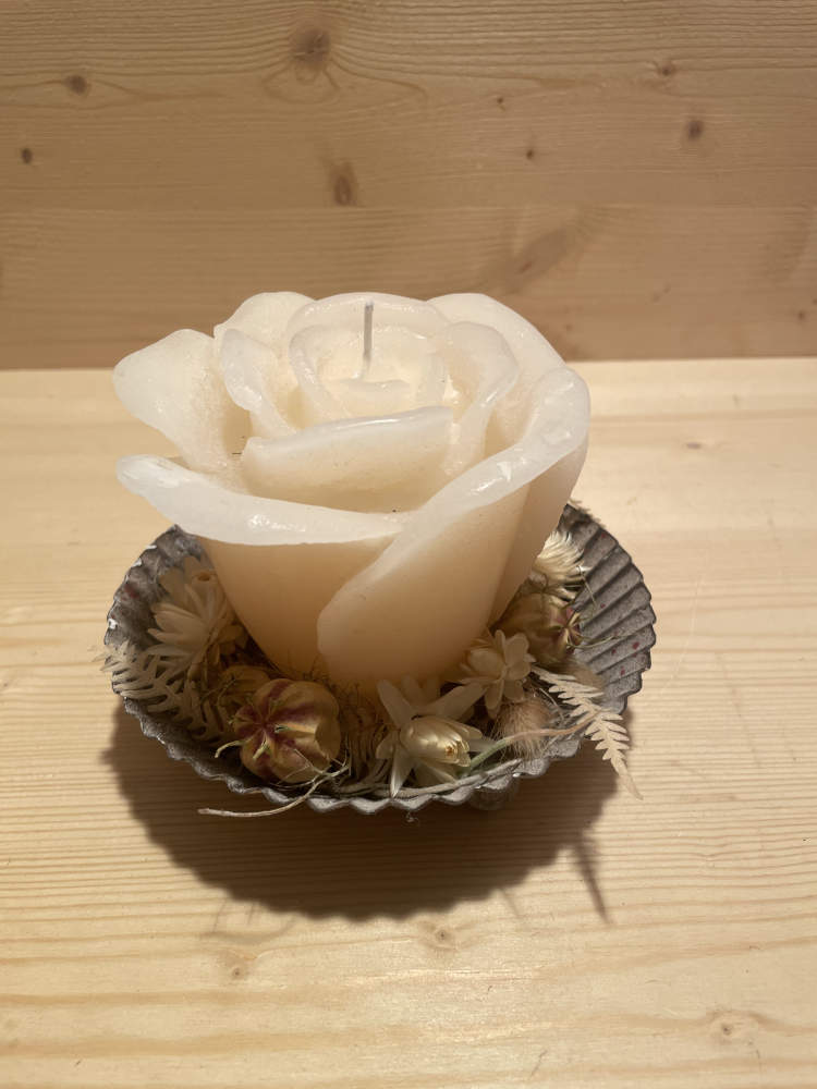 Rosenkerze in creme auf einem Teller ausgarniert