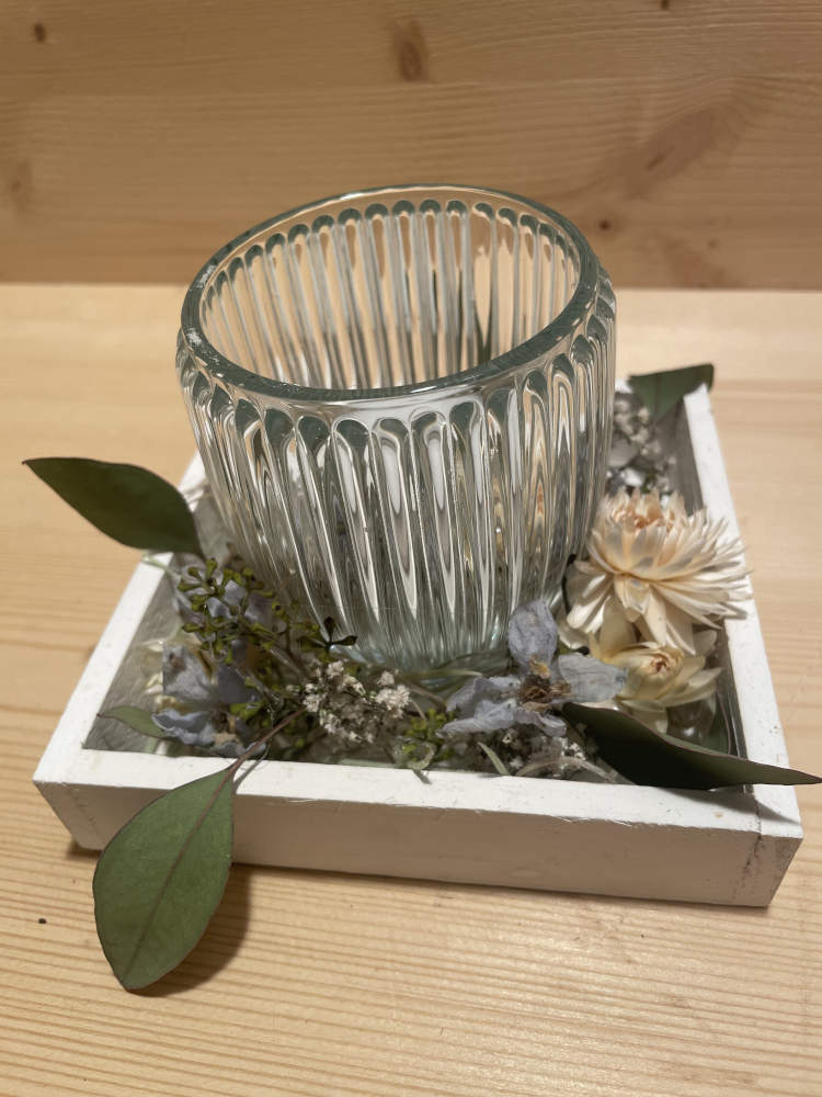 Kerze mit Glas auf einem Holzbrett ausgarniert